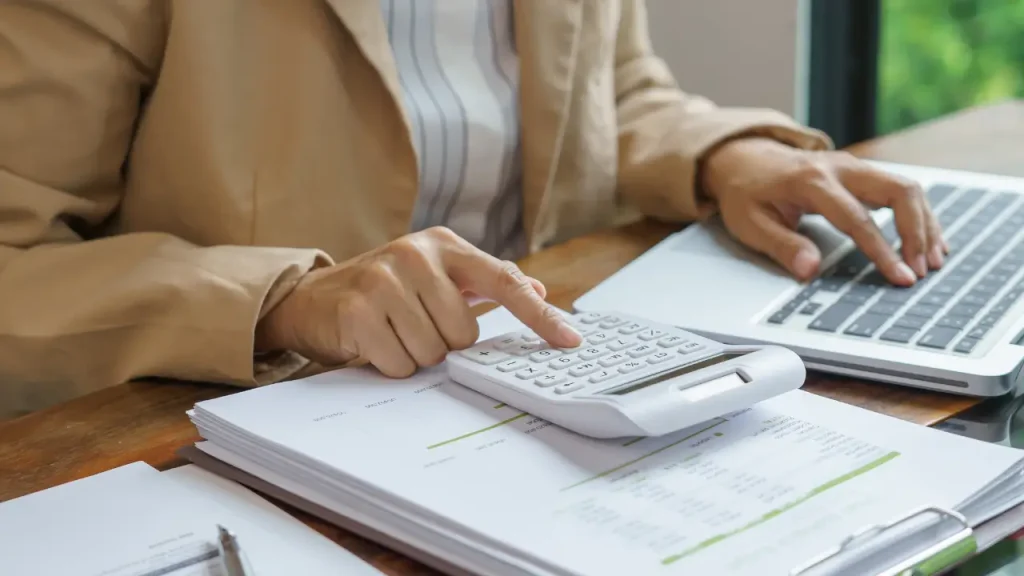 Mulher usando computador e calculadora para melhorar estresse financeiro
